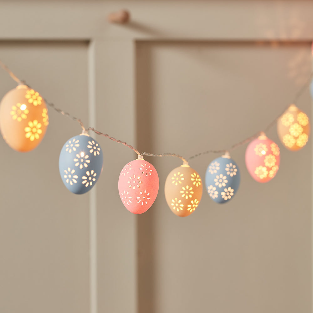 Lichterkette mit pastellfarbenen Ostereiern in Rosa, Blau und Gelb mit Blumenmuster beleuchtet