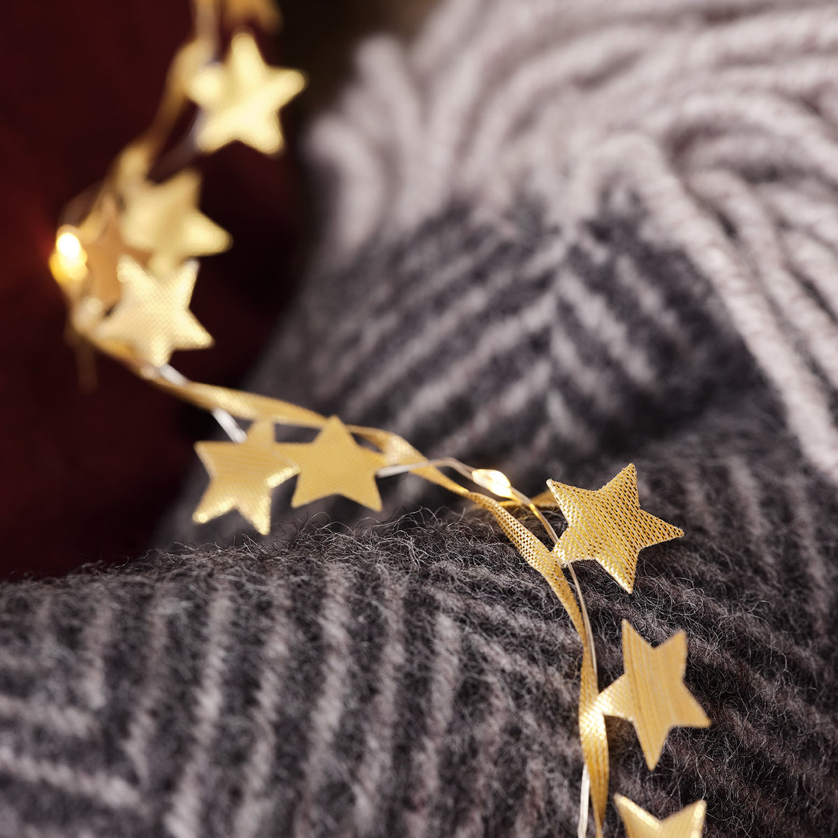 Goldene Stoffsterne mit warmweißen LEDs auf grauem Wollstoff