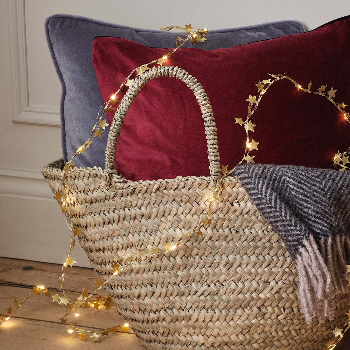 Goldene Stern-Girlande mit LEDs dekorativ in geflochtenem Korb mit Kissen und Decke