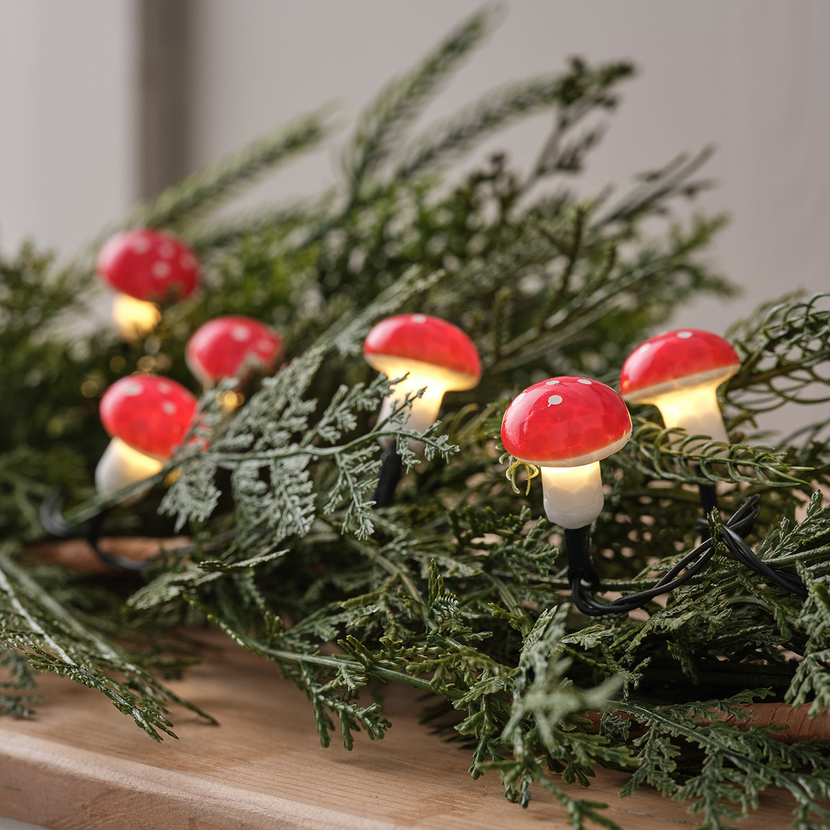 LED Lichterkette mit roten Fliegenpilzen und warmweißem Licht auf grünen Zweigen