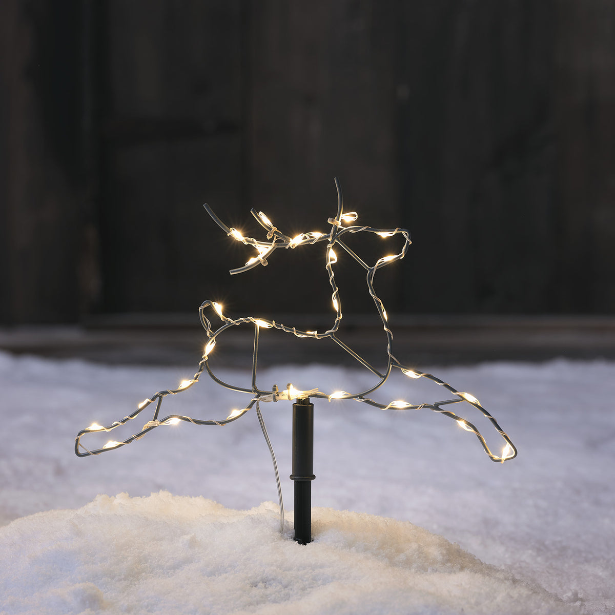 Nahaufnahme eines LED-Rentiers mit warmweißen Lichtern im Schnee
