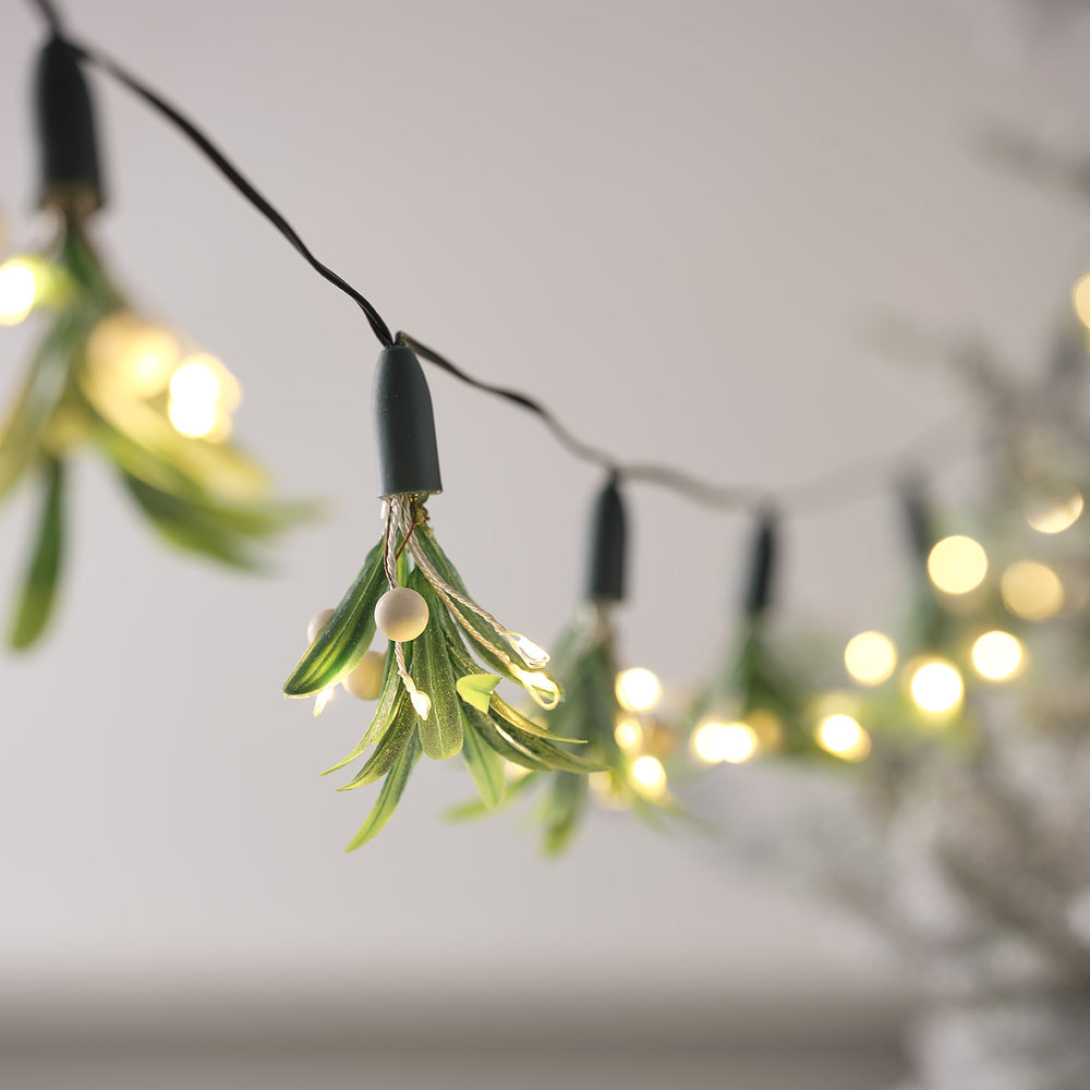 Nahaufnahme einer Micro LED Lichterkette mit künstlichen Mistelzweigen und weißen Beeren
