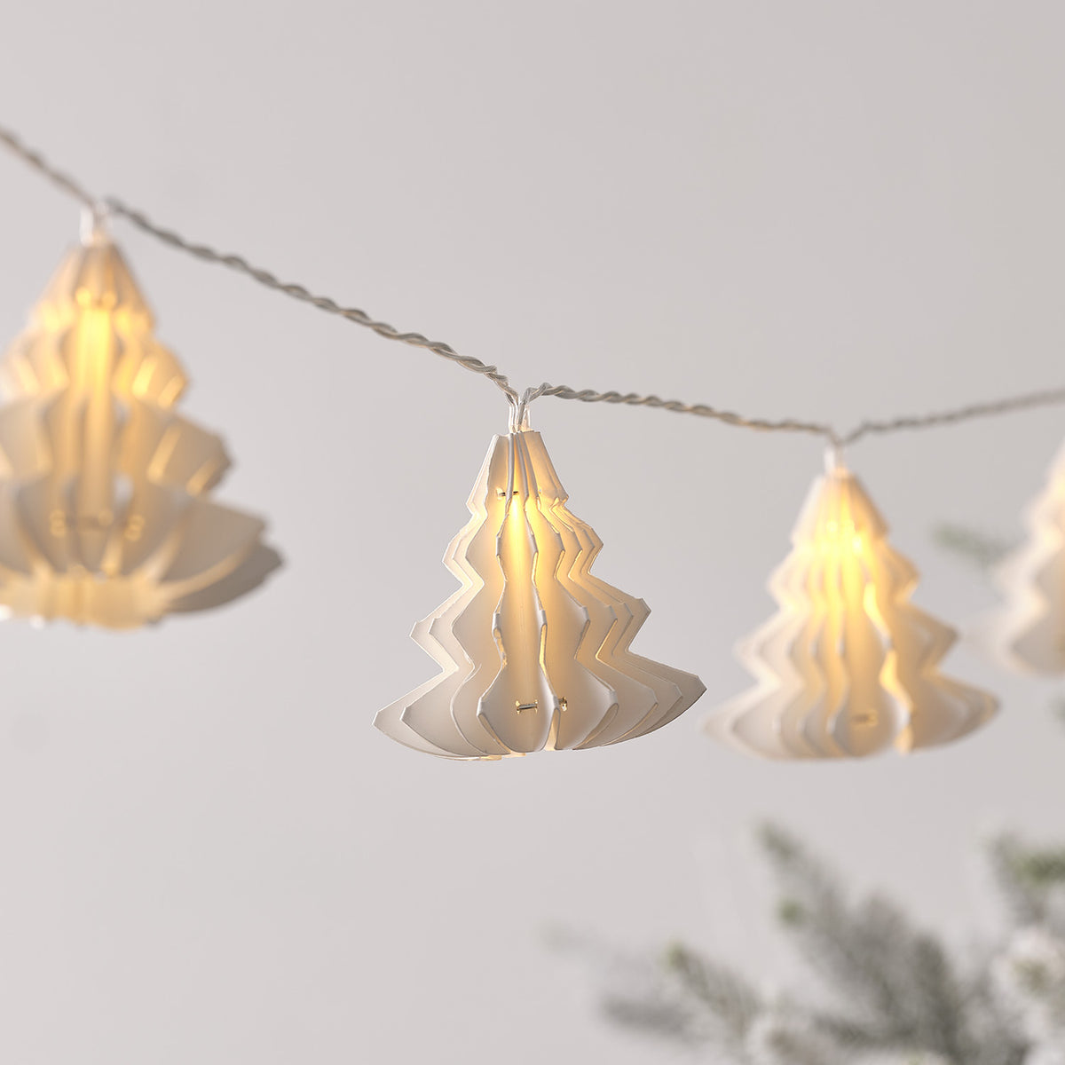 Nahaufnahme einer weißen LED-Lichterkette mit Papierbäumen und warmweißem Licht