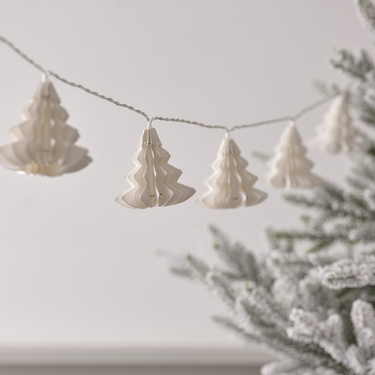 Weiße Papierbäume an einer LED-Lichterkette ohne eingeschaltete LEDs