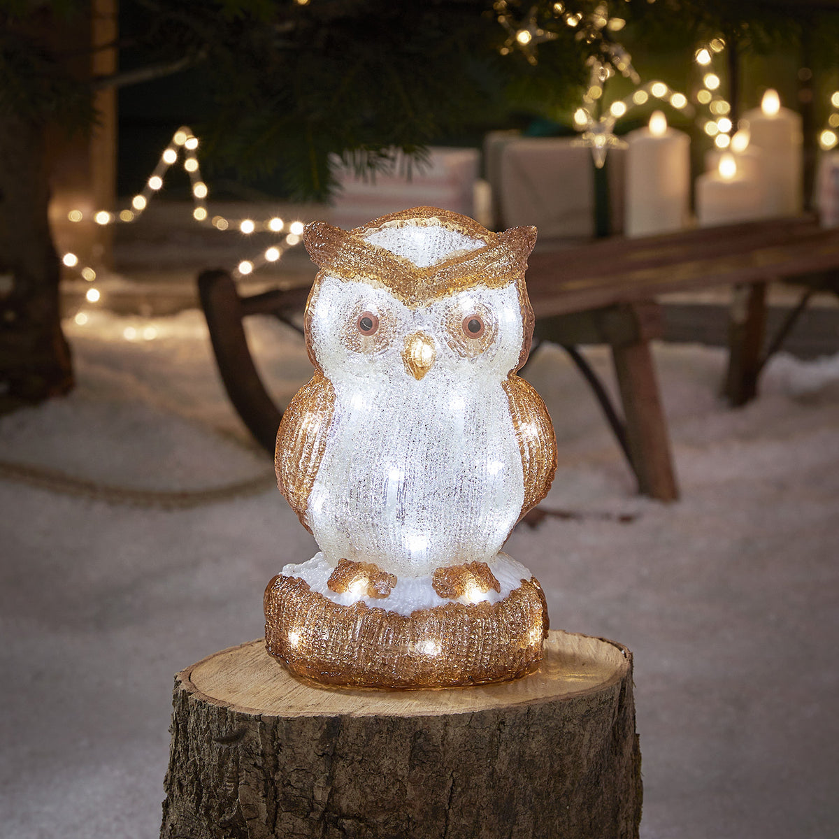 Beleuchtete Acryl-Eulenfigur mit weißen LEDs auf Baumstumpf im Schnee vor Weihnachtsdeko