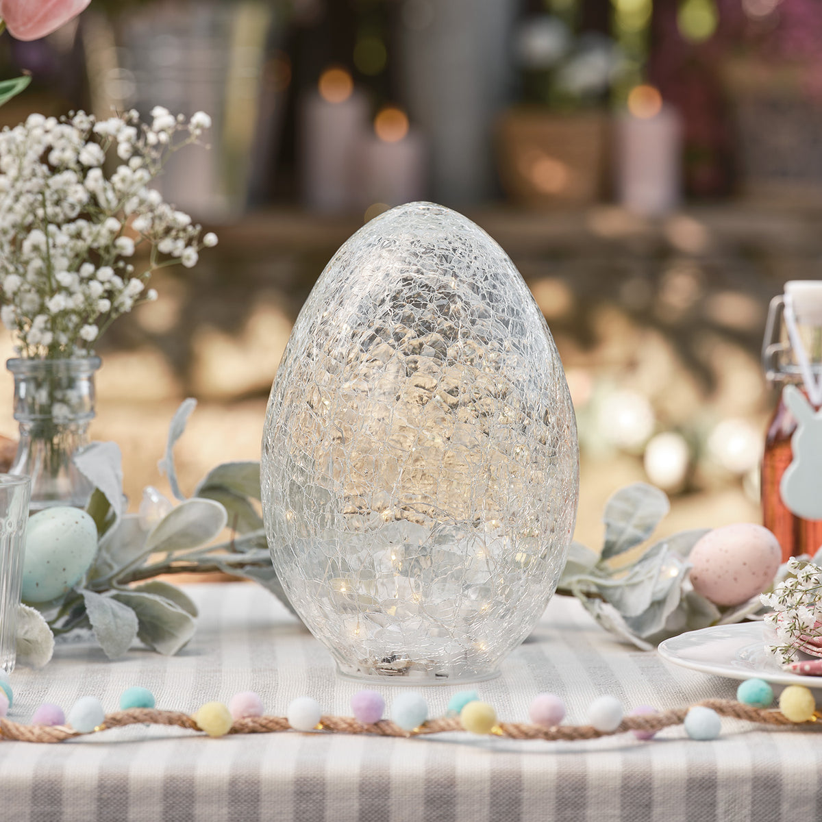 Beleuchtetes Glasosterei mit Crackle-Struktur auf Ostertisch mit Deko