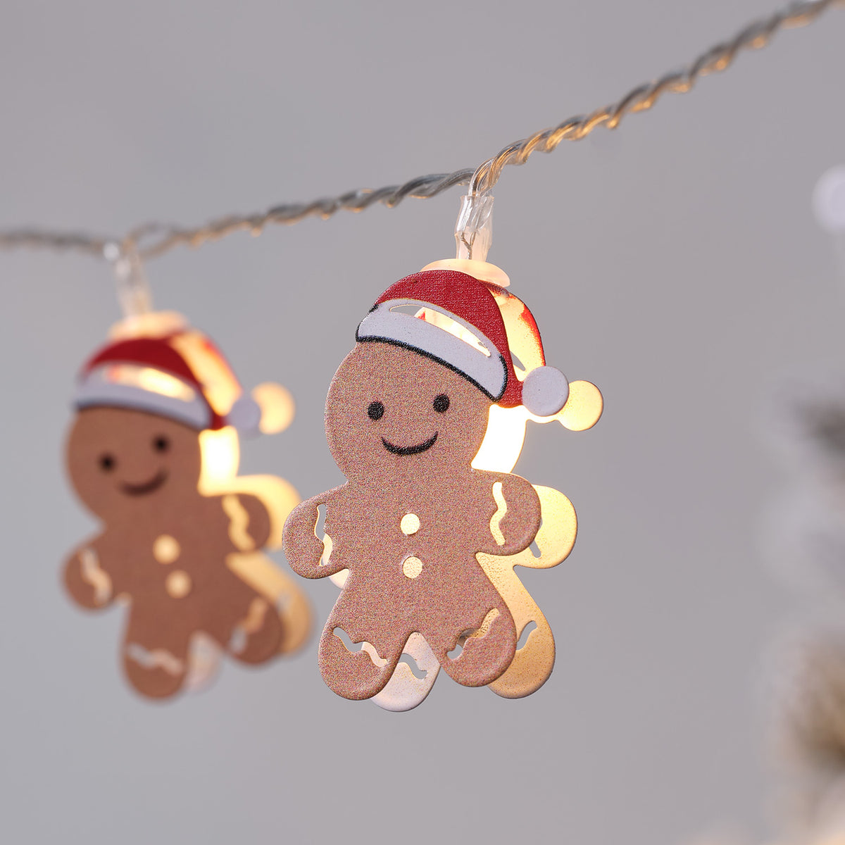Detailaufnahme eines beleuchteten Lebkuchenmännchens mit Weihnachtsmütze an Lichterkette