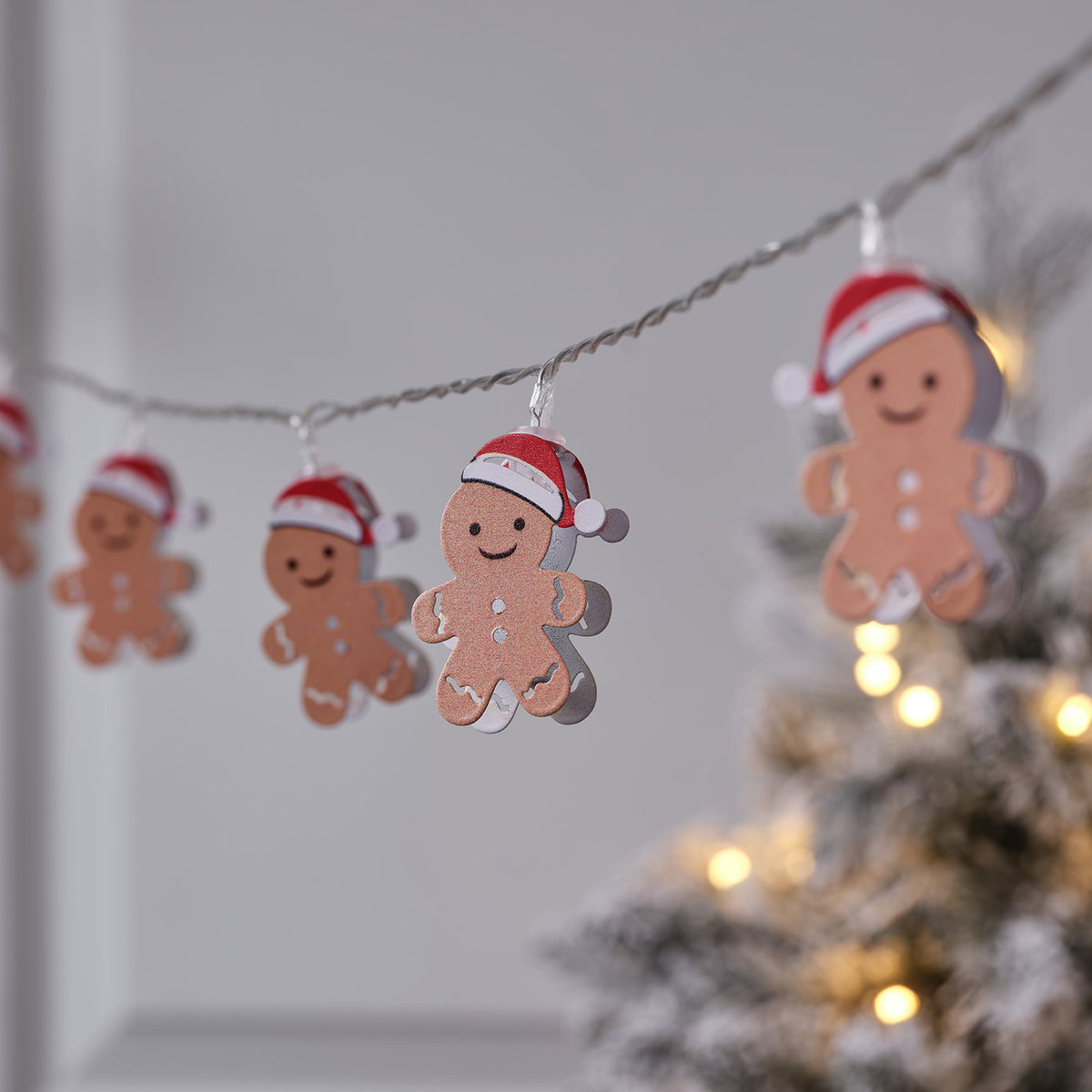 LED-Lichterkette mit Lebkuchenmännchen in Weihnachtsmütze vor unscharfem Hintergrund