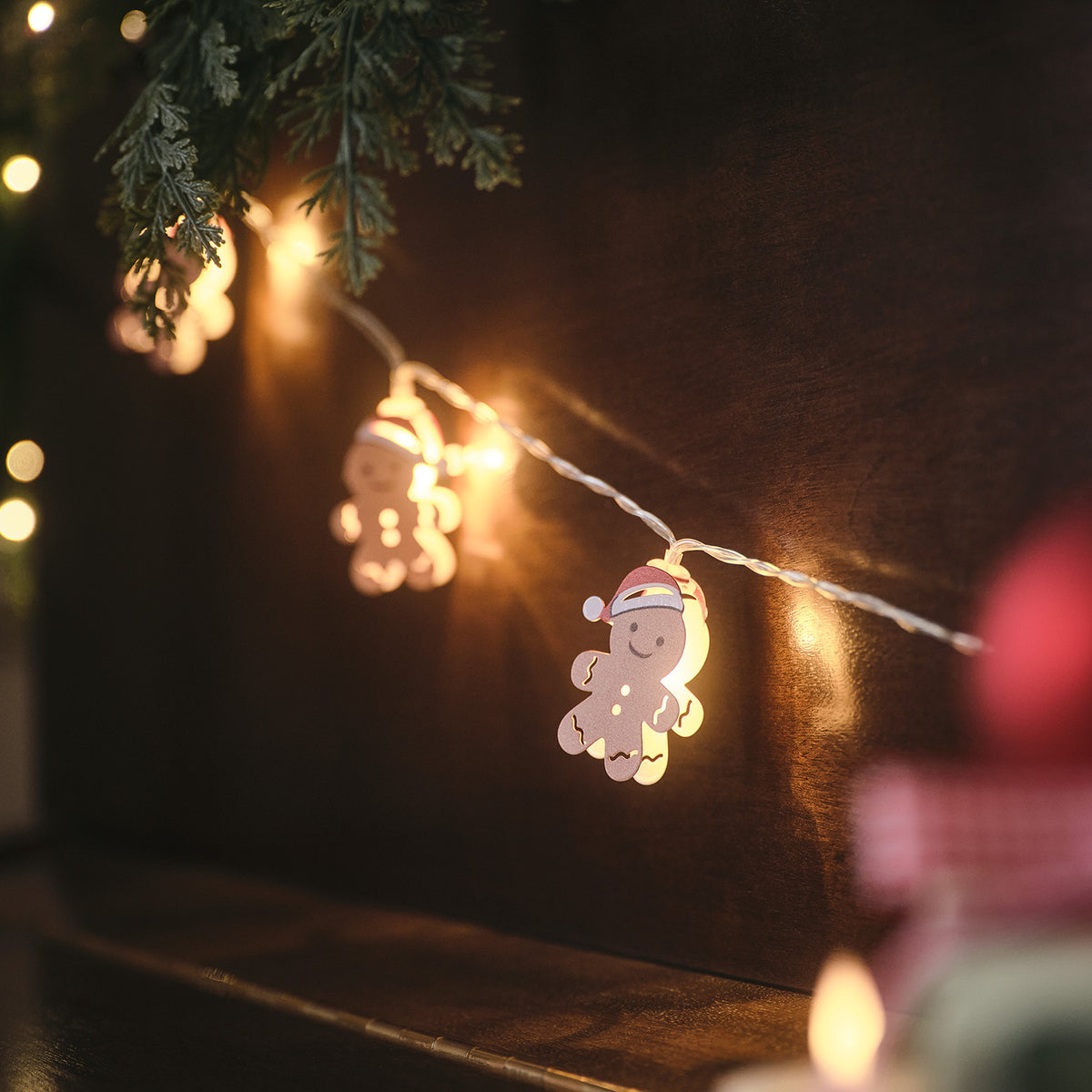 LED-Lichterkette mit Lebkuchenmännchen leuchtet warmweiß an dunklem Holz