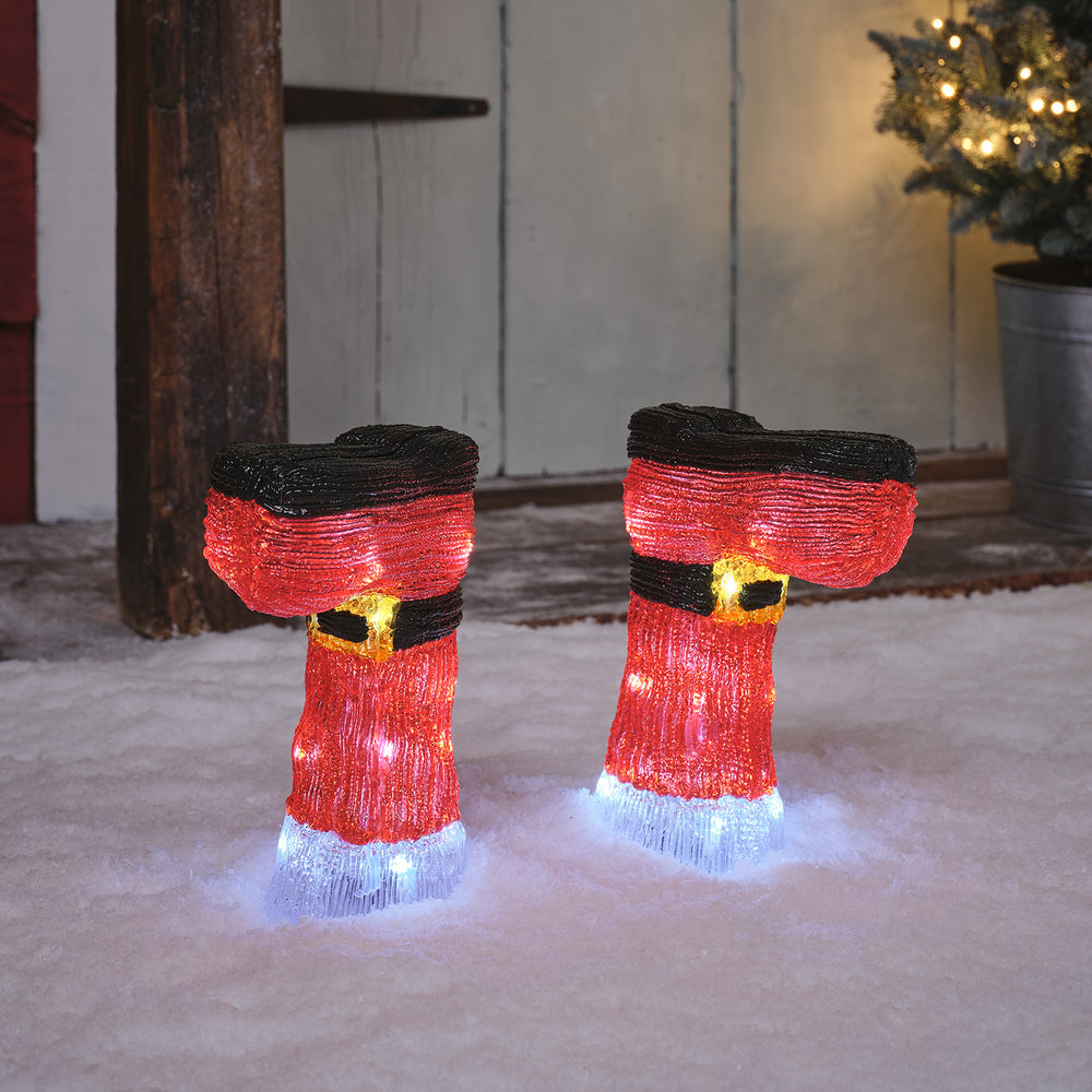 Leuchtende Weihnachtsstiefel mit roten und weißen LED-Lichtern im Schnee vor einer Haustür