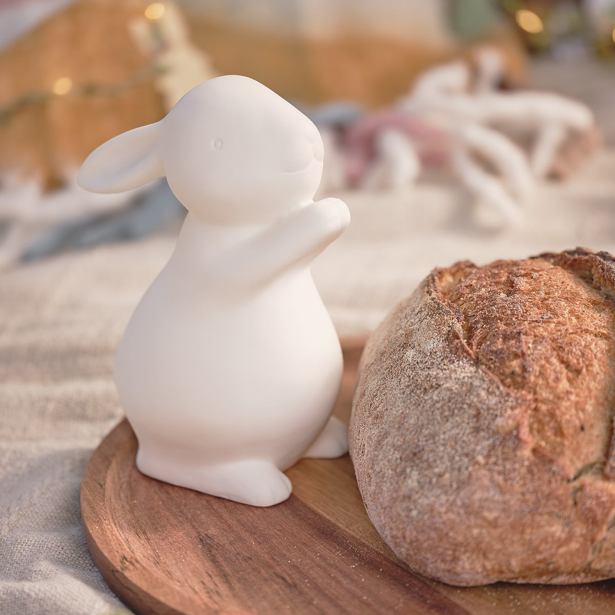 Porzellan-Osterhase neben Brot auf Holzbrett in rustikalem Ambiente