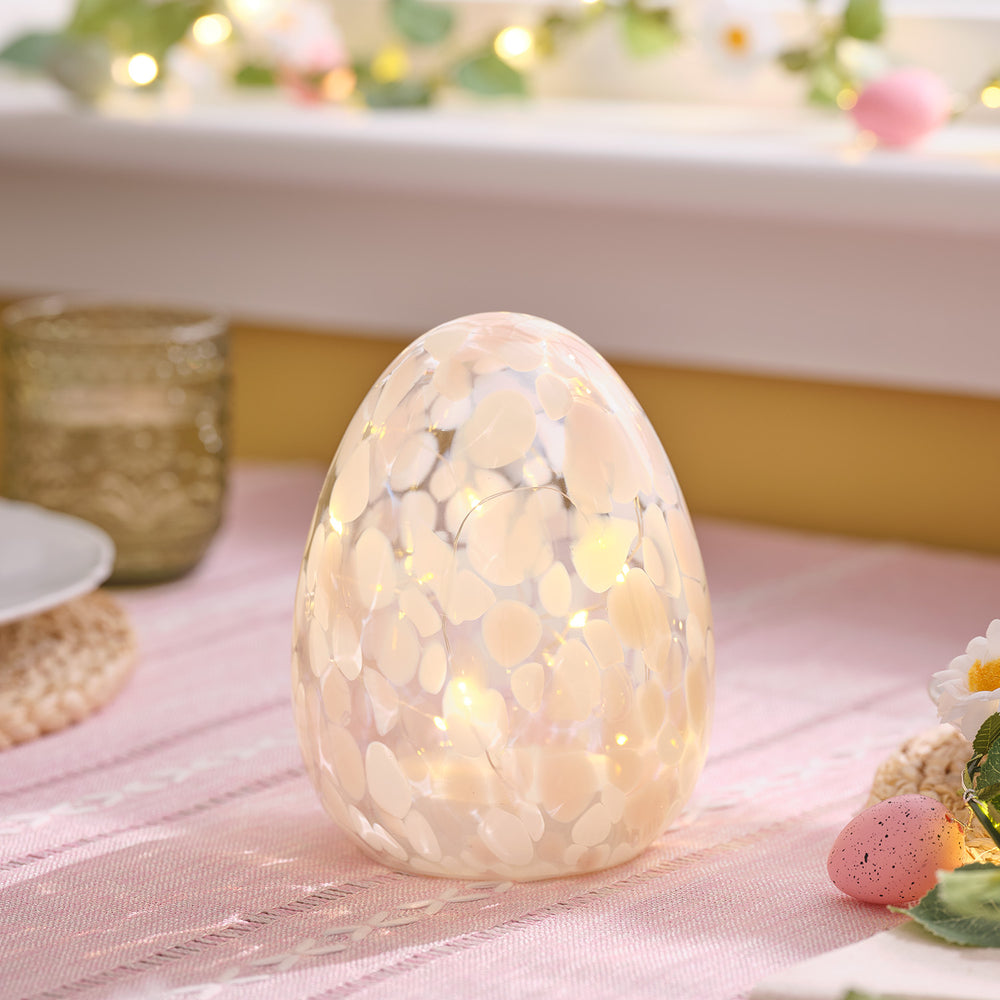 Pastellrosa LED-Osterei aus handgeblasenem Glas mit Konfetti-Muster auf rosa Tischdecke