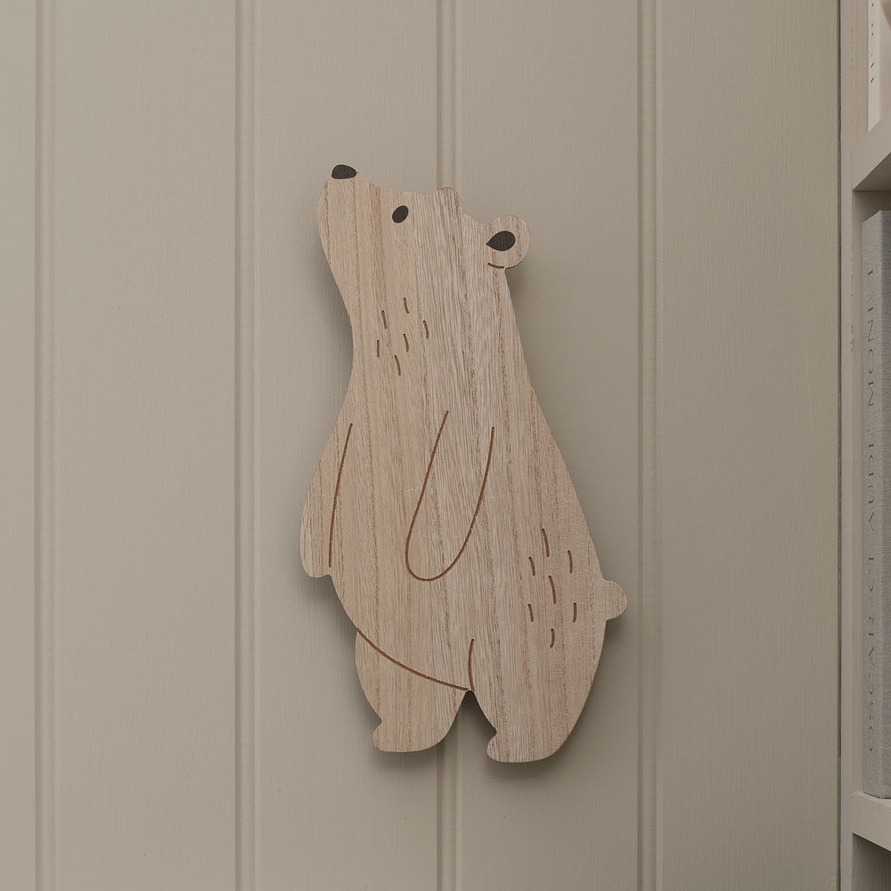 Holz-Wandlampe in Bärform ohne Licht an weißer Wand neben Regal mit Büchern