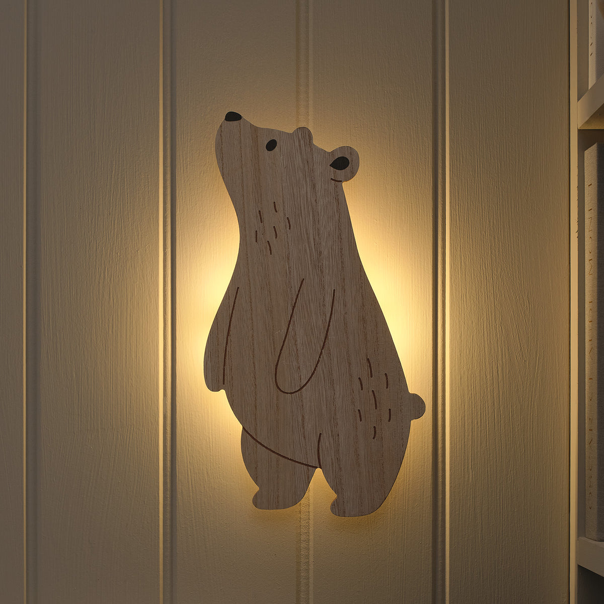 Holz-Wandlampe in Bärform mit warmweißem Licht an weißer Wand im Kinderzimmer