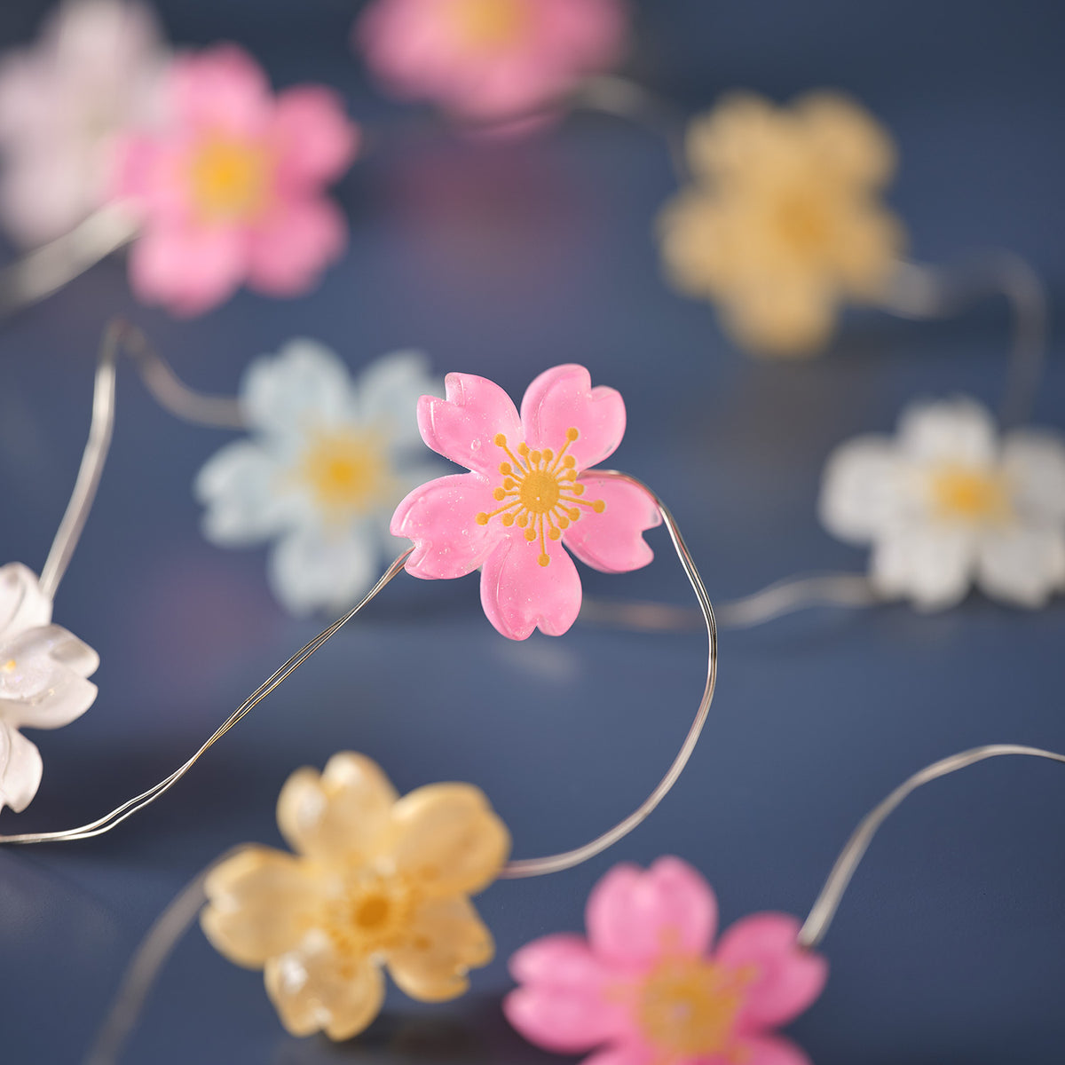 Nahaufnahme einer pinkfarbenen Blüte mit warmweißer LED auf transparenter Kabellichterkette