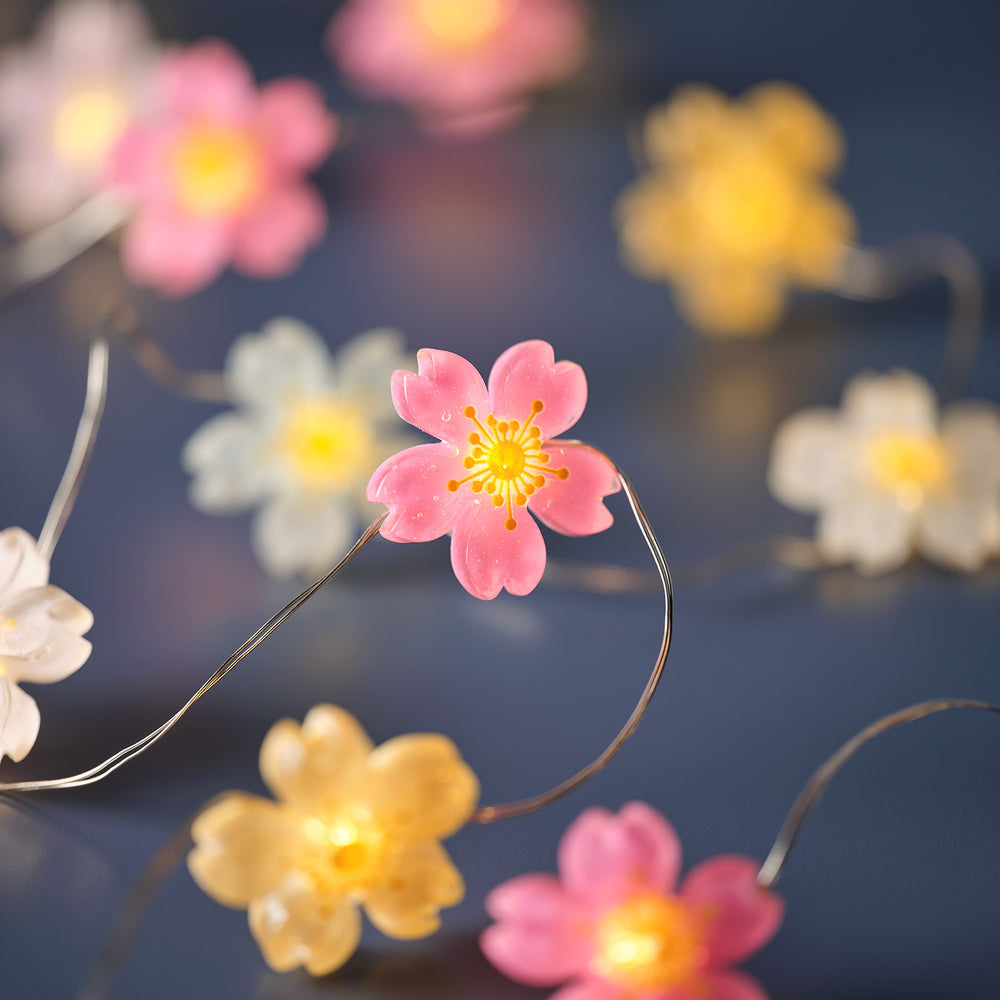 Nahaufnahme einer pinkfarbenen Blüte mit warmweißer LED auf transparenter Kabellichterkette