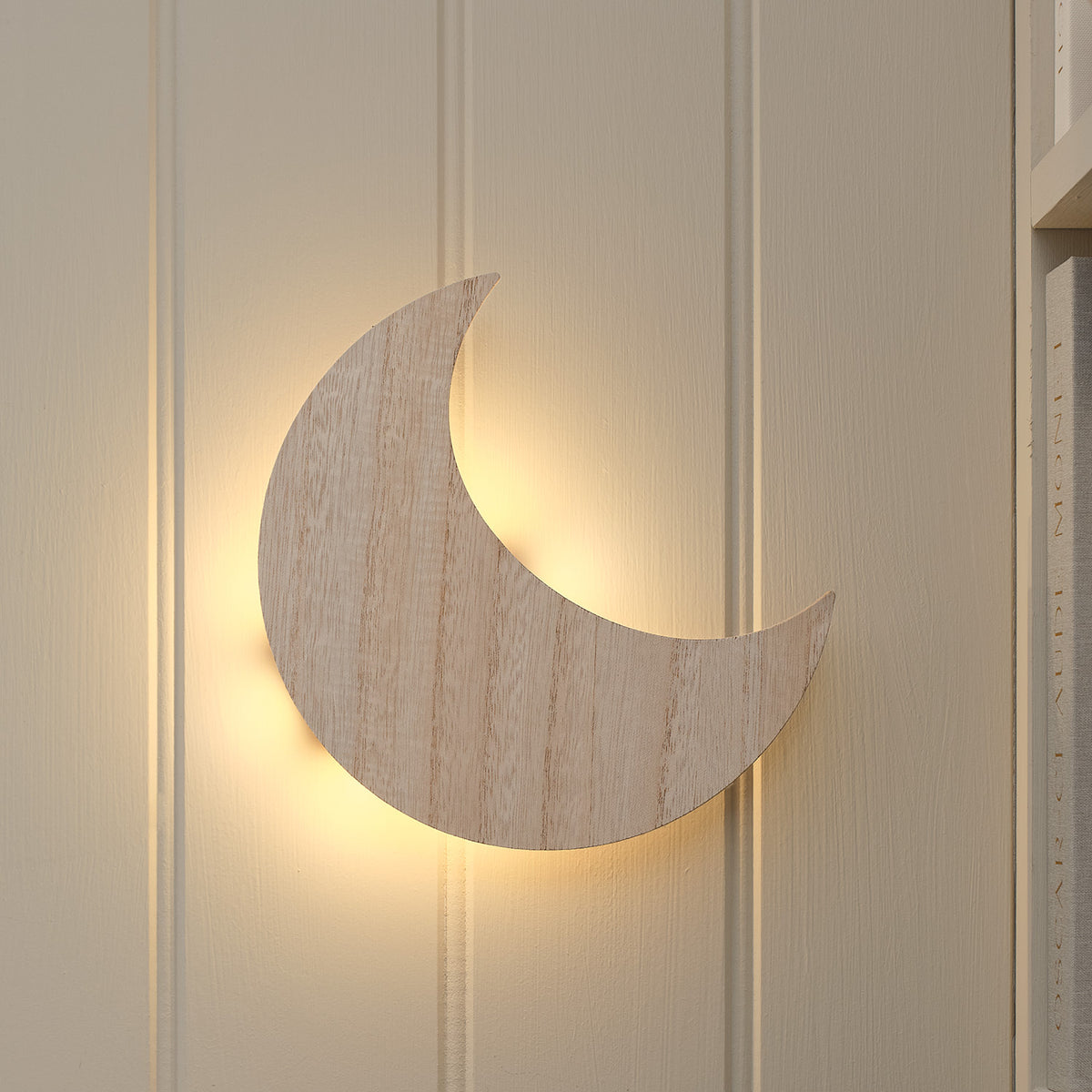Wandlampe in Form eines Halbmonds aus Holz mit sanftem warmweißem Licht im Kinderzimmer