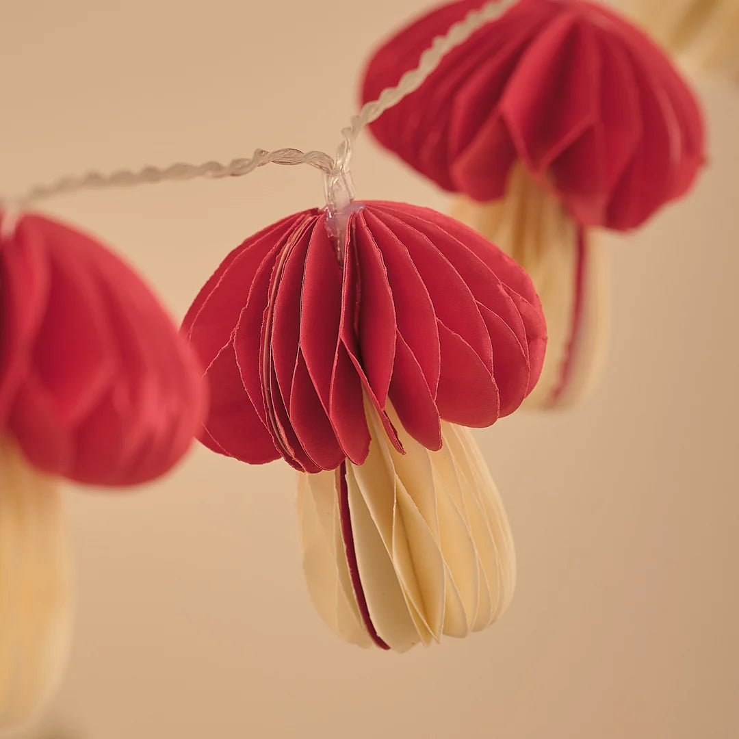Roter Papier-Pilz-Anhänger an Lichterkette, Nahaufnahme.