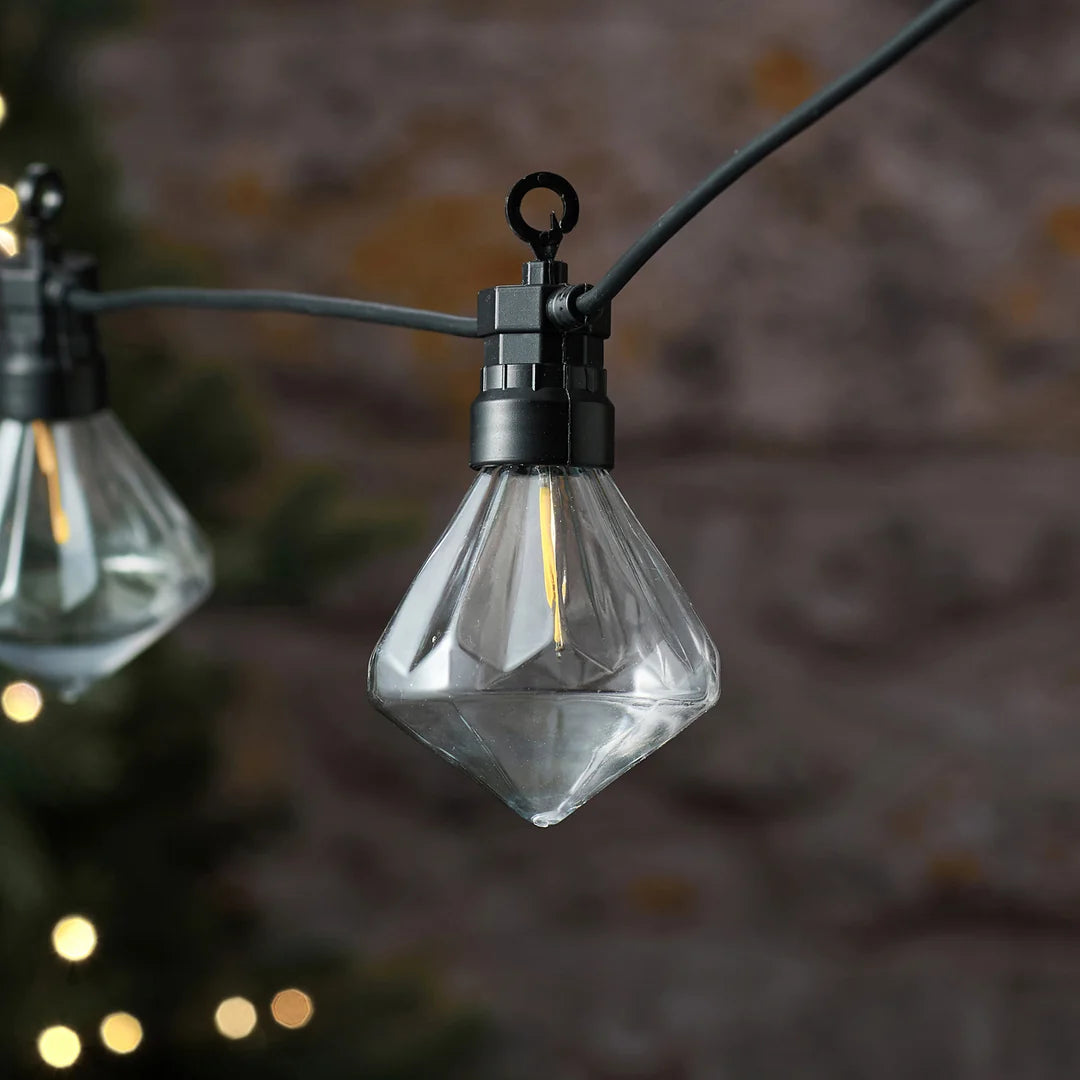 Detailansicht einer klaren diamantförmigen LED-Glühbirne an Lichterkette.