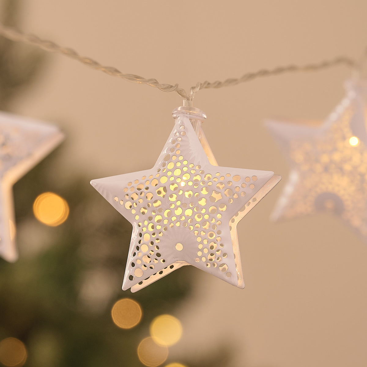 Nahaufnahme eines weißen Metallsterns mit filigranen Ausschnitten und warmweißem LED-Licht
