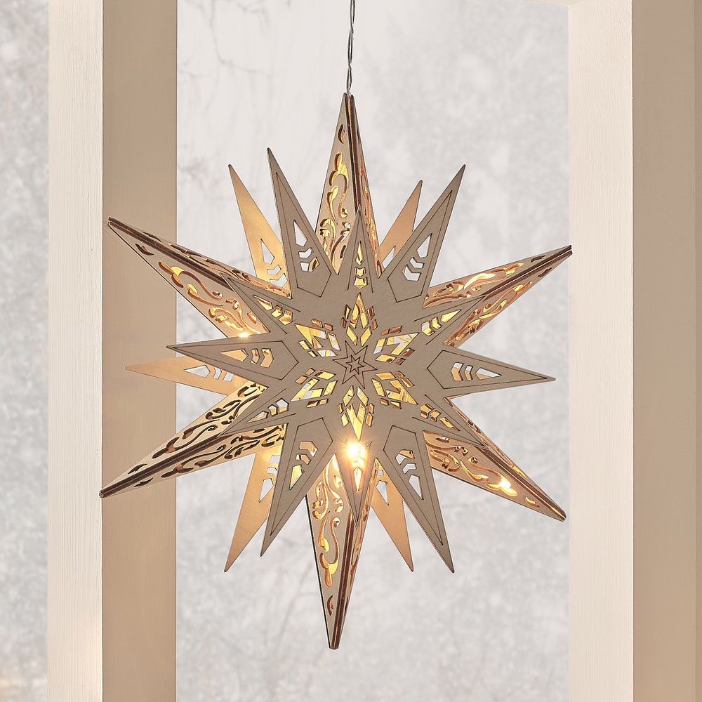 Sechszackiger LED-Holzstern mit warmweißen LEDs und filigranen Ausschnitten, hängend vor hellem Fenster