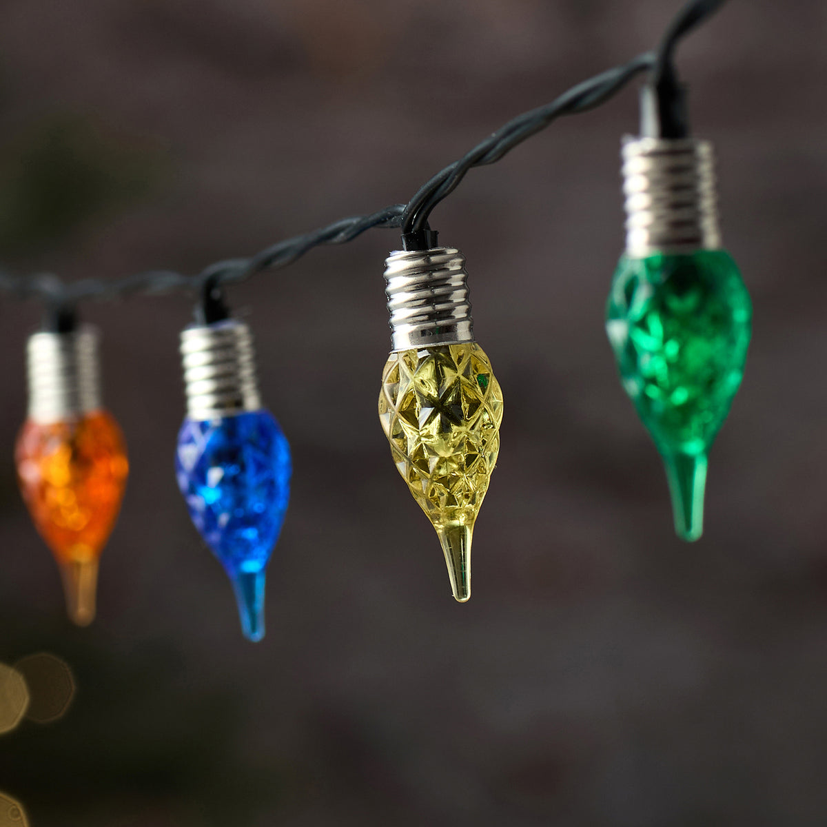 Detailaufnahme mehrerer bunter LED-Glastropfen an schwarzem Kabel der Lichterkette