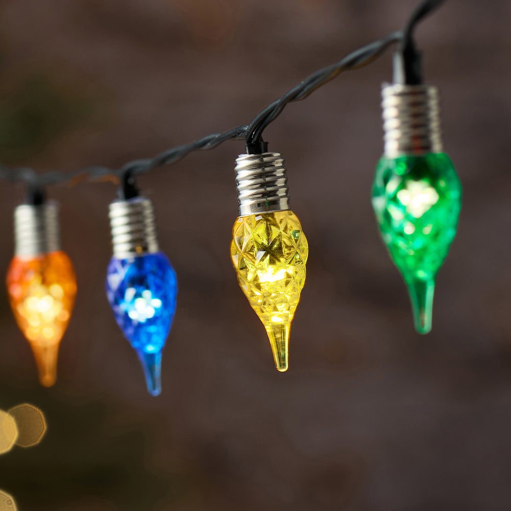 Nahaufnahme bunter facettierter Glastropfen der LED-Lichterkette mit schwarzem Kabel
