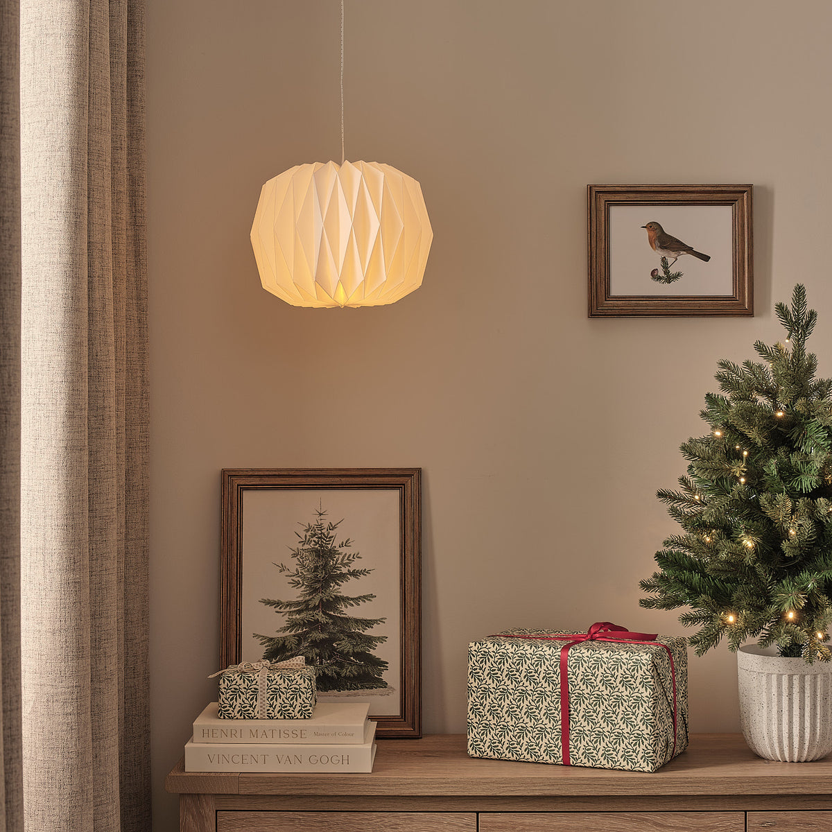 Weiße LED-Papierlaterne ohne Licht an grauer Wand neben Weihnachtsbaum und Geschenken