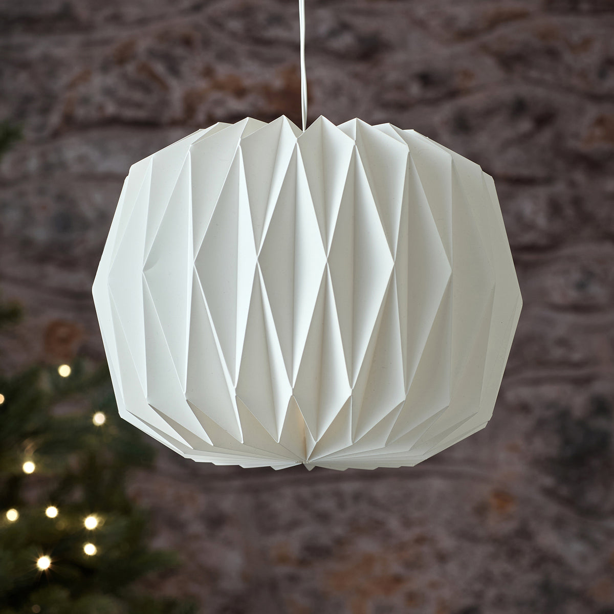 Nahaufnahme weiße LED-Papierlaterne mit warmweißem Licht vor Steinwand