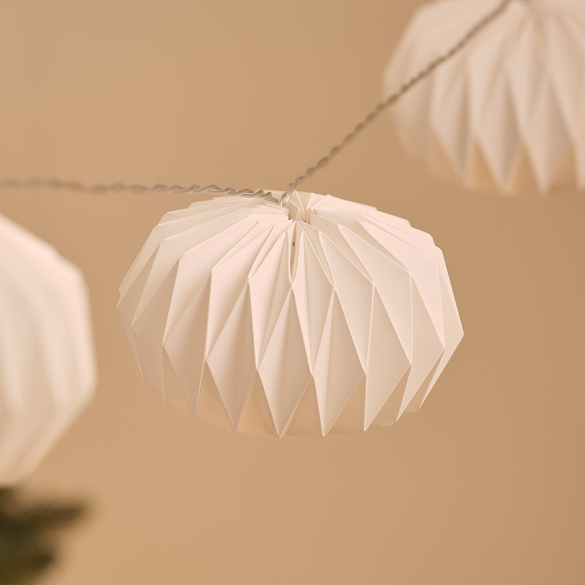 Unbeleuchtete weiße Papierlampions an transparenter LED-Lichterkette vor unscharfem Hintergrund