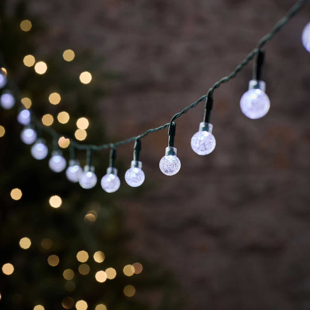 Nahaufnahme der weißen Bubble Ball LEDs mit grünem Kabel und unscharfem Hintergrund