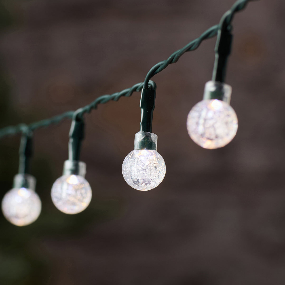 Weiße LED-Kugeln der Bubble Ball Lichterkette mit grünem Kabel im Außenbereich