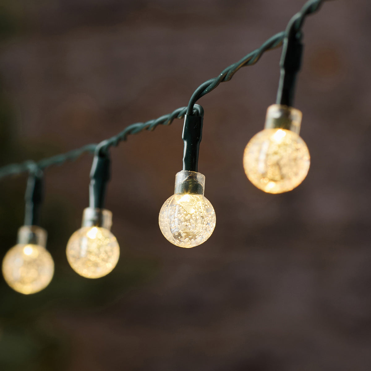 Nahaufnahme der kugeligen Bubble Ball LEDs mit warmweißem Licht an grünem Kabel