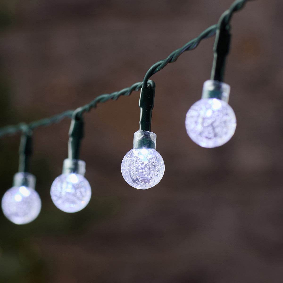 Nahaufnahme der weißen Bubble Ball LED mit grünem Kabel und unscharfem Hintergrund