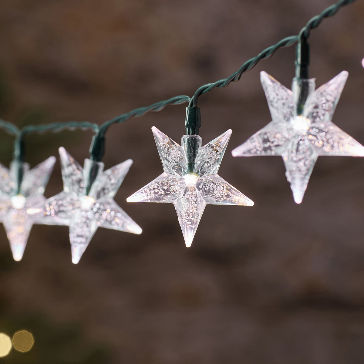 Nahaufnahme eines weiß leuchtenden Sterns der LED-Lichterkette mit grünem Kabel