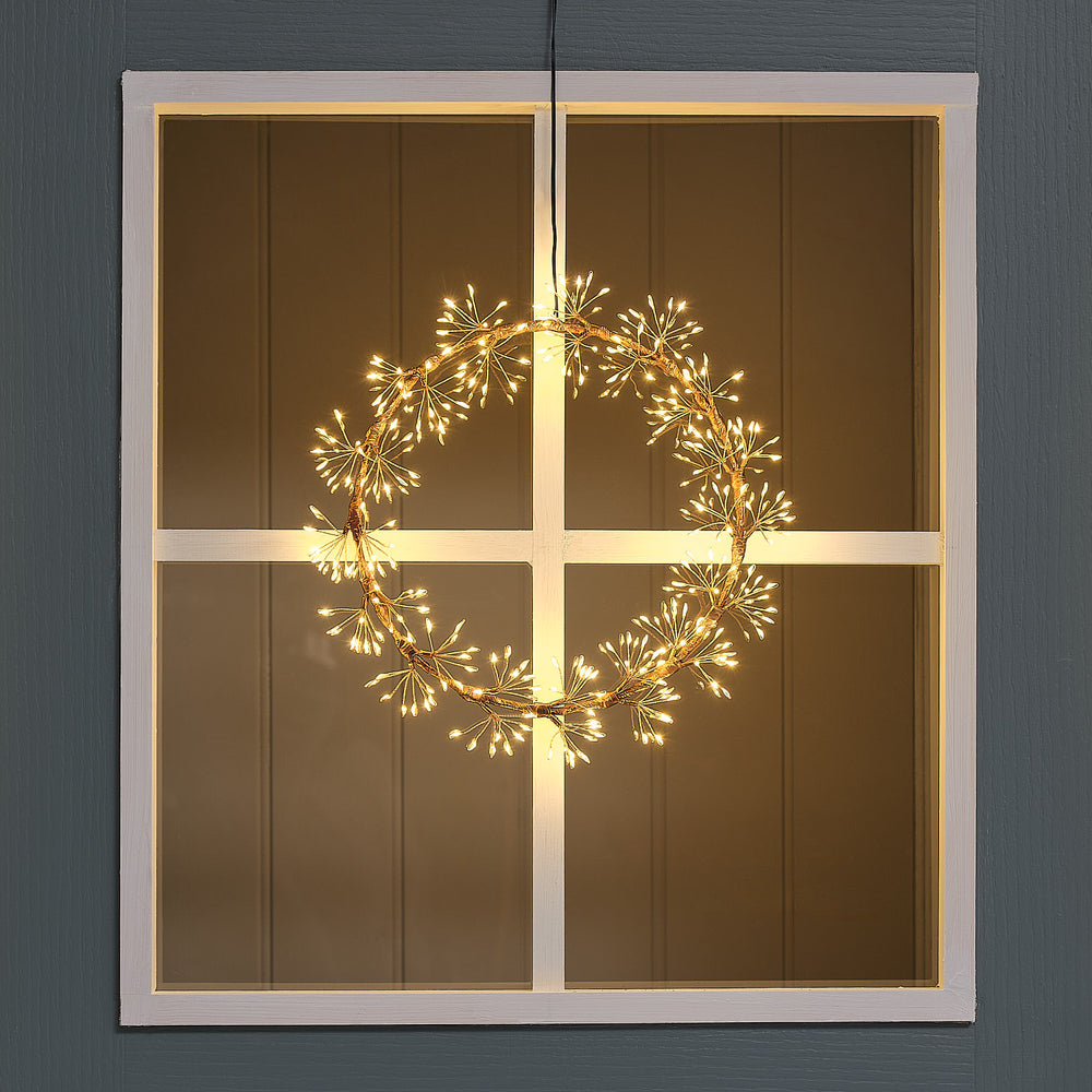 Beleuchteter goldener LED-Lichterkranz mit 256 Mikro-LEDs hängt an Fenster mit weißen Sprossen