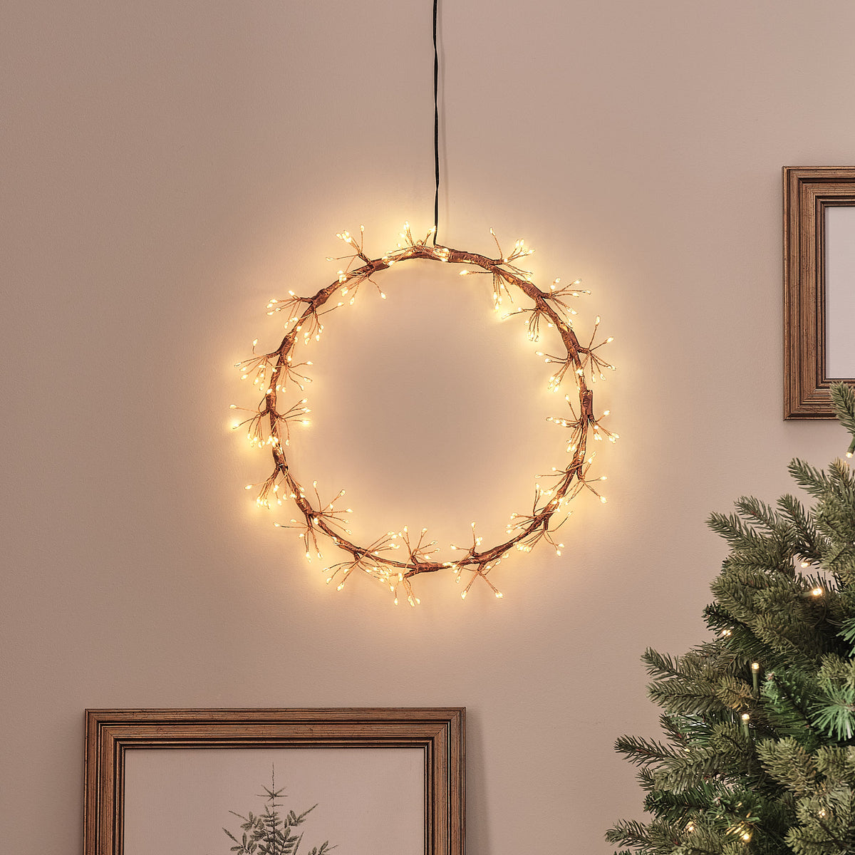 Goldener Starburst LED-Lichterkranz mit warmweißen Mikro-LEDs an Wand über Weihnachtsbaum