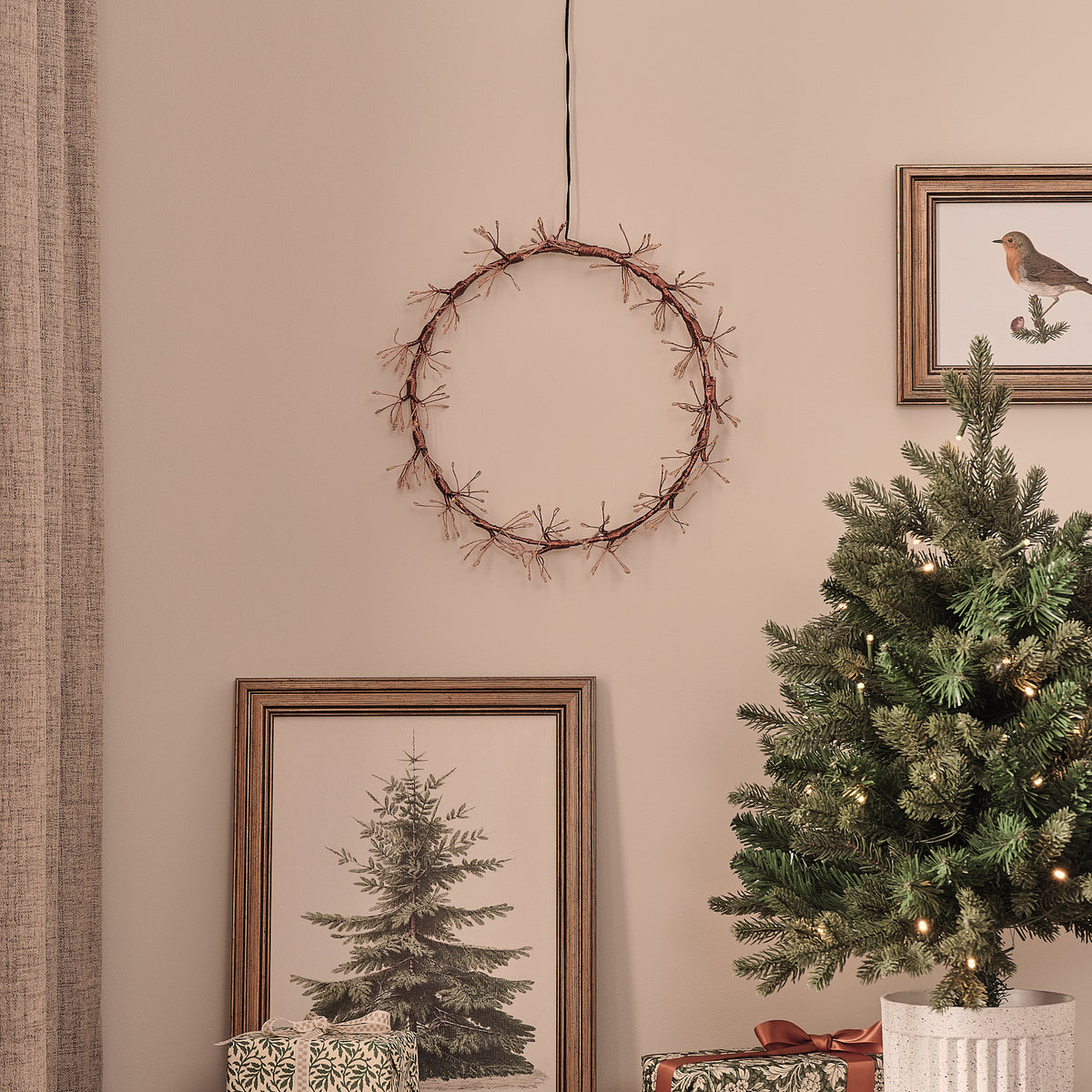 Goldener LED-Lichterkranz ohne Beleuchtung an Wand über Weihnachtsbaum und Bilderrahmen