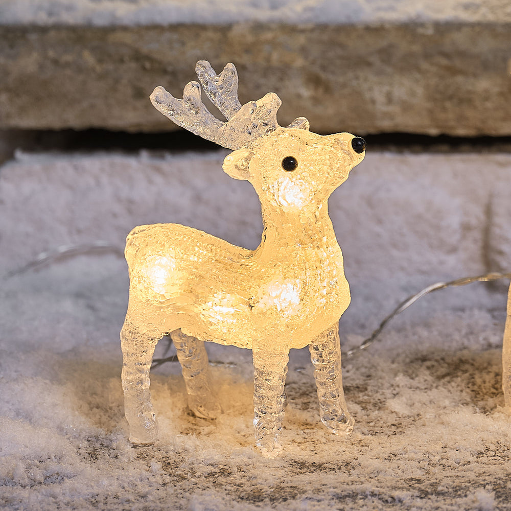 Nahaufnahme eines leuchtenden Acryl-Rentiers mit schwarzen Knopfaugen und Geweih im Schnee