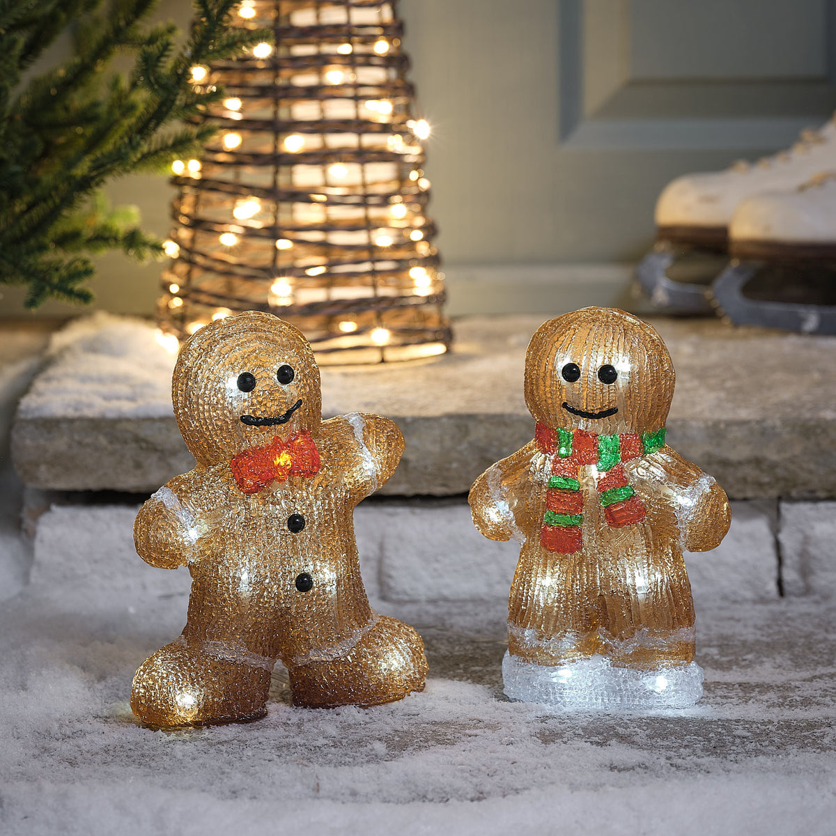 Zwei beleuchtete LED-Lebkuchenmänner aus Acryl mit rotem Fliegenband und rot-grün gestreiftem Schal im Schnee