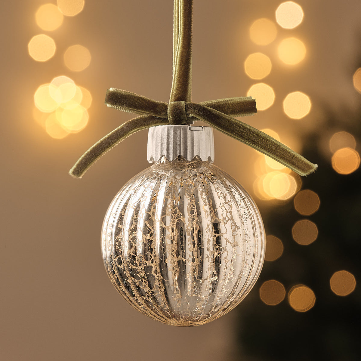Nahaufnahme einer einzelnen LED-Weihnachtskugel aus geriffeltem Glas mit grüner Schleife