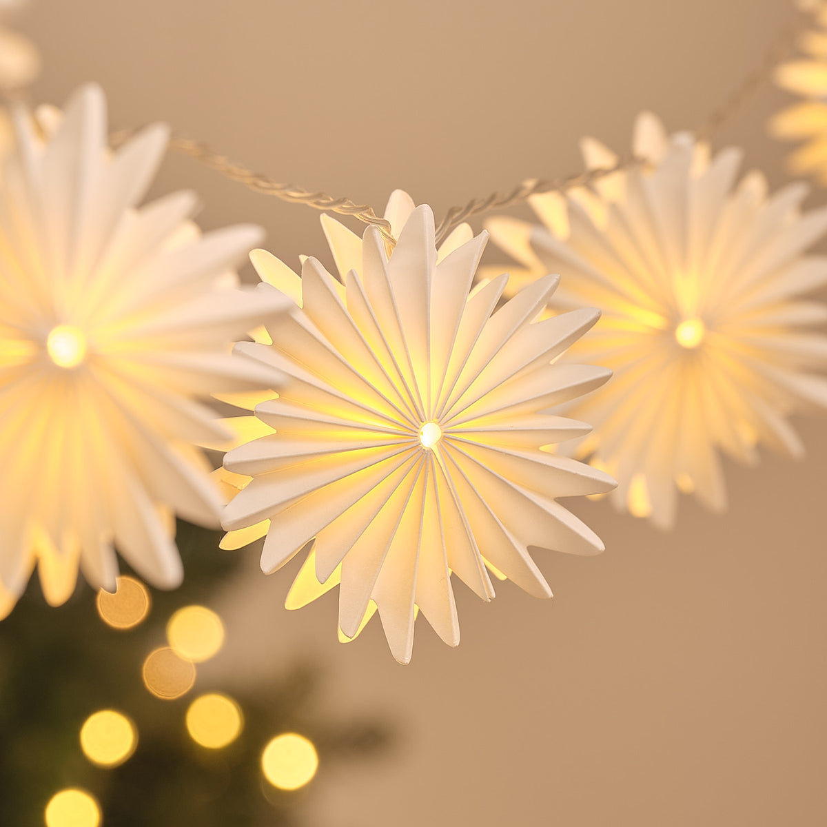 Nahaufnahme einer warmweiß leuchtenden Papier-Schneeflocke der LED-Lichterkette