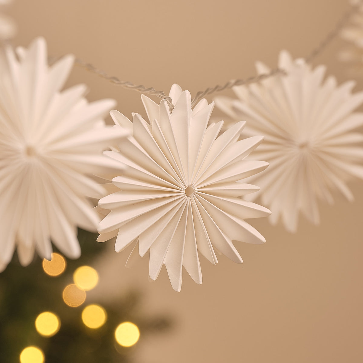 Detailaufnahme einer weißen Papier-Schneeflocke der LED-Lichterkette mit warmweißem Licht