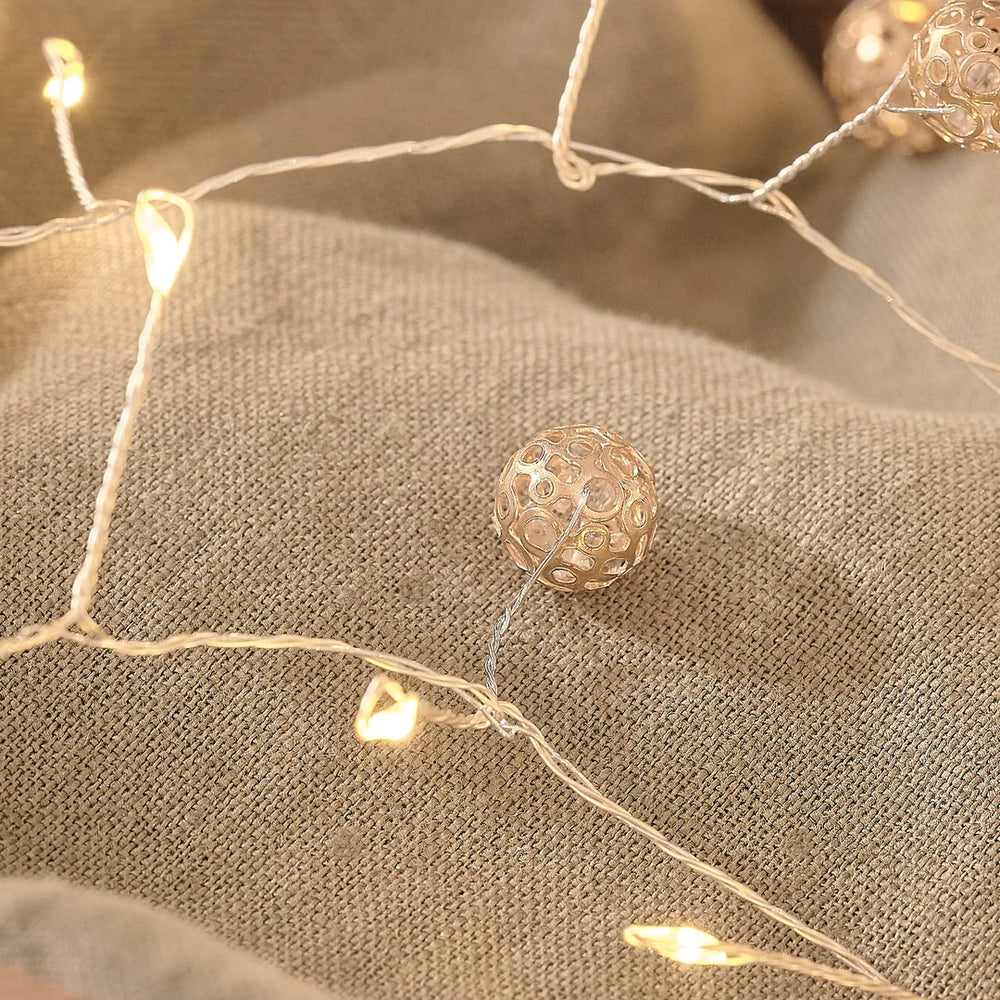 Detailaufnahme einer Premium-LED-Lichterkette mit warmweißen Glühbirnen und cremefarbenen Organza-Schleifenakzenten, arrangiert auf elegantem cremefarbenem Leinenstoff – hochwertige Dekoration-Lichterkette für stilvolle Weihnachts-Arrangements, Tischdekoration und elegante Raumaromatisierung.