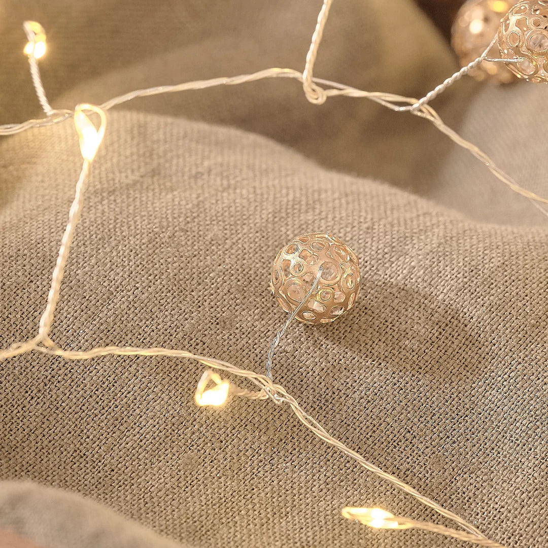 Detailaufnahme einer Premium-LED-Lichterkette mit warmweißen Glühbirnen und cremefarbenen Organza-Schleifenakzenten, arrangiert auf elegantem cremefarbenem Leinenstoff – hochwertige Dekoration-Lichterkette für stilvolle Weihnachts-Arrangements, Tischdekoration und elegante Raumaromatisierung.