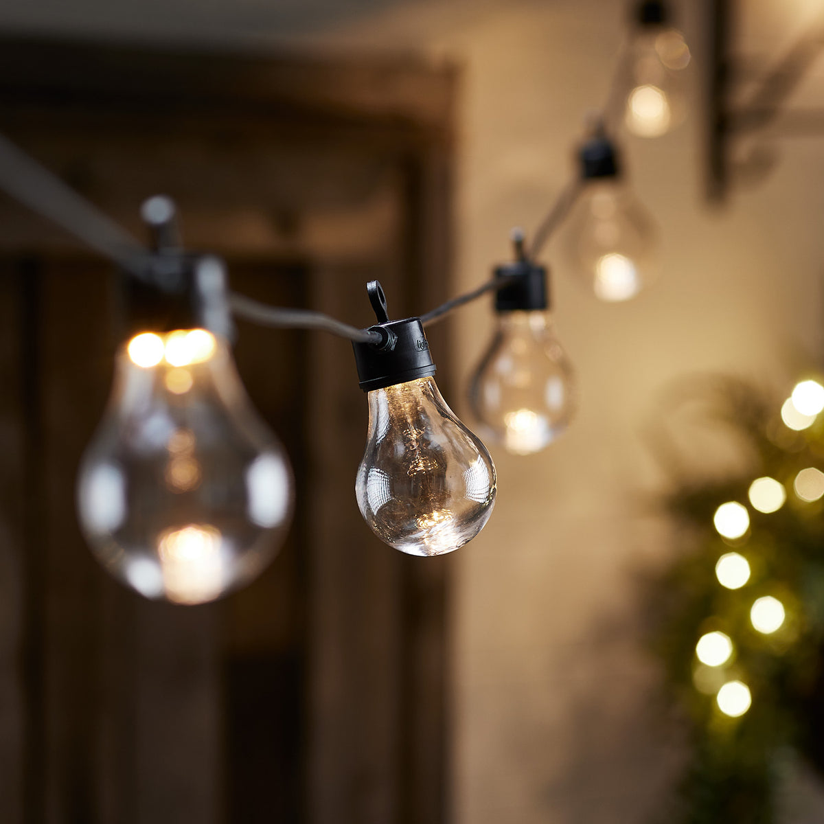 Nahaufnahme einer Glühbirne der Lichterkette mit unscharfen Lichtern im Hintergrund