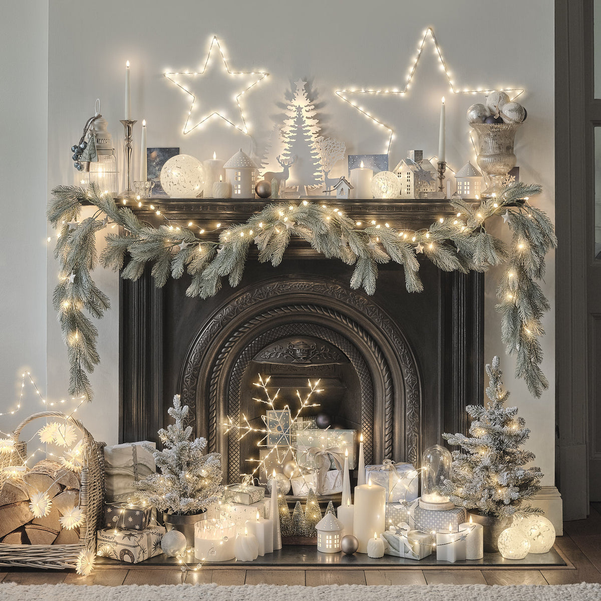 Weihnachtlich dekorierter Kamin mit LED-Lichterketten, Kerzen und Tannenzweigen im Scandi-Stil