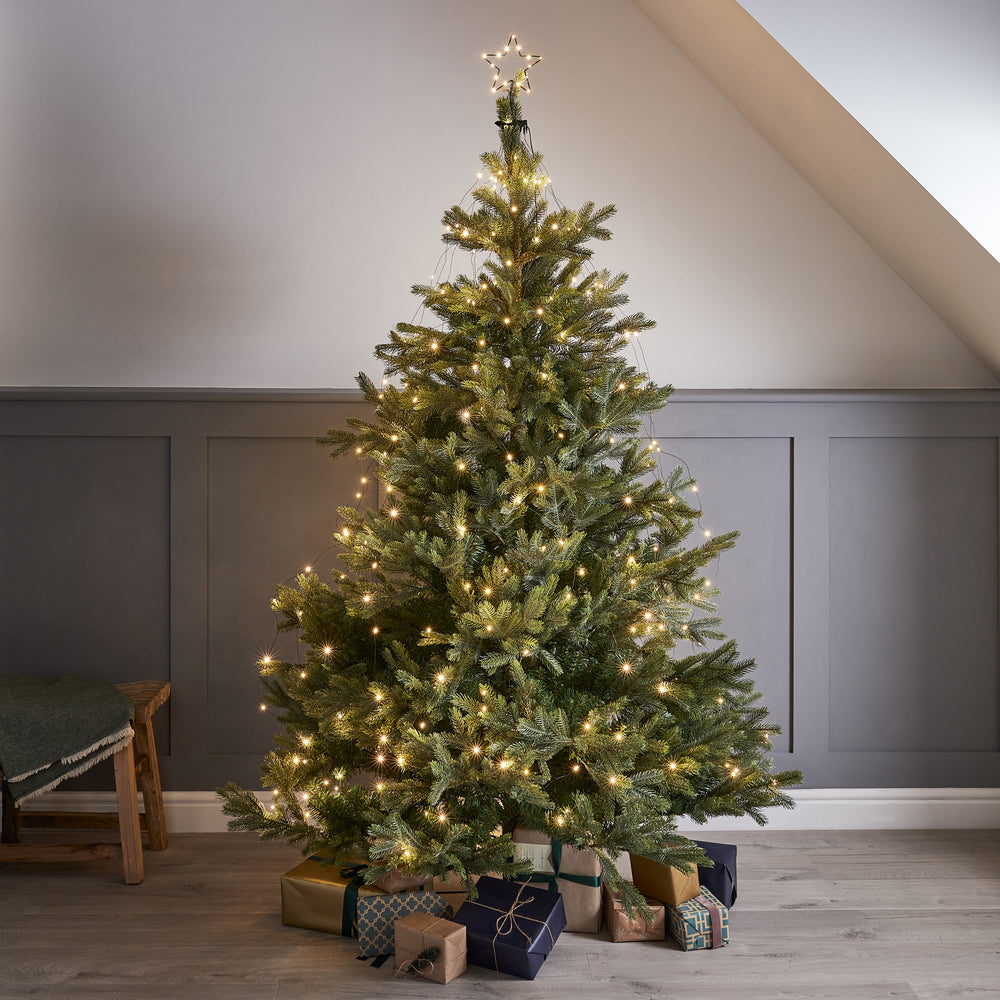 Weihnachtsbaum mit warmweißen LED-Lichterketten und beleuchtetem Stern als Baumspitze in einem Raum