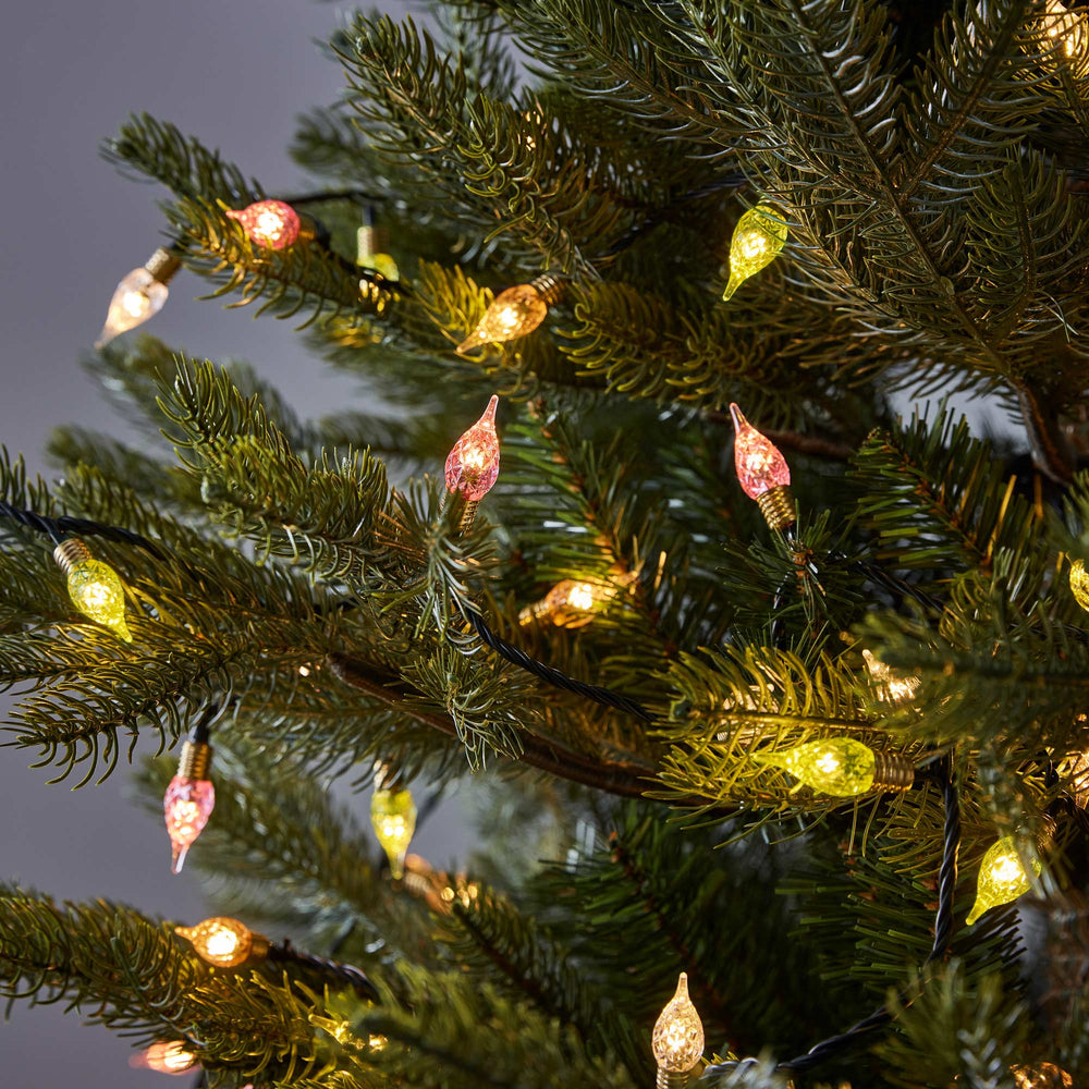 Bunte LED-C9-Glühbirnen in Pastellfarben an einem Weihnachtsbaum mit grünem Kabel