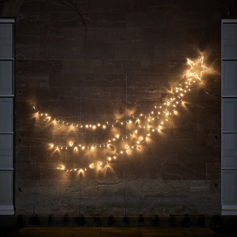 Bicolor LED Sternschnuppe mit warmweiß leuchtenden Lichtsträngen an dunkler Wand